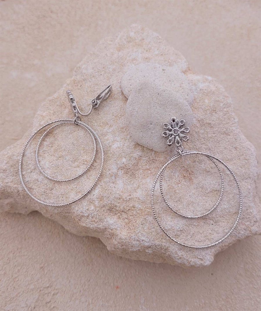 Boucles d'oreilles à clip avec 2 anneaux rhodiées et un clip en forme de fleur.